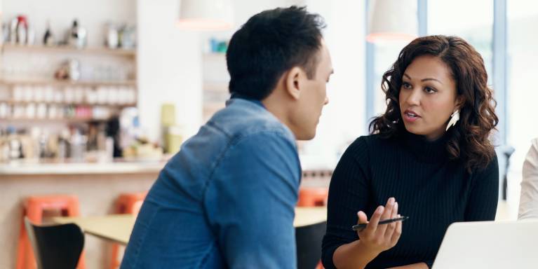 Two people talking in front of laptop