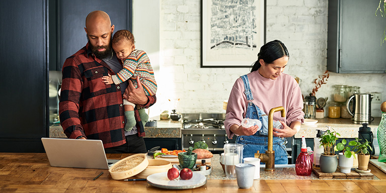 Man holding baby while looking at laptop